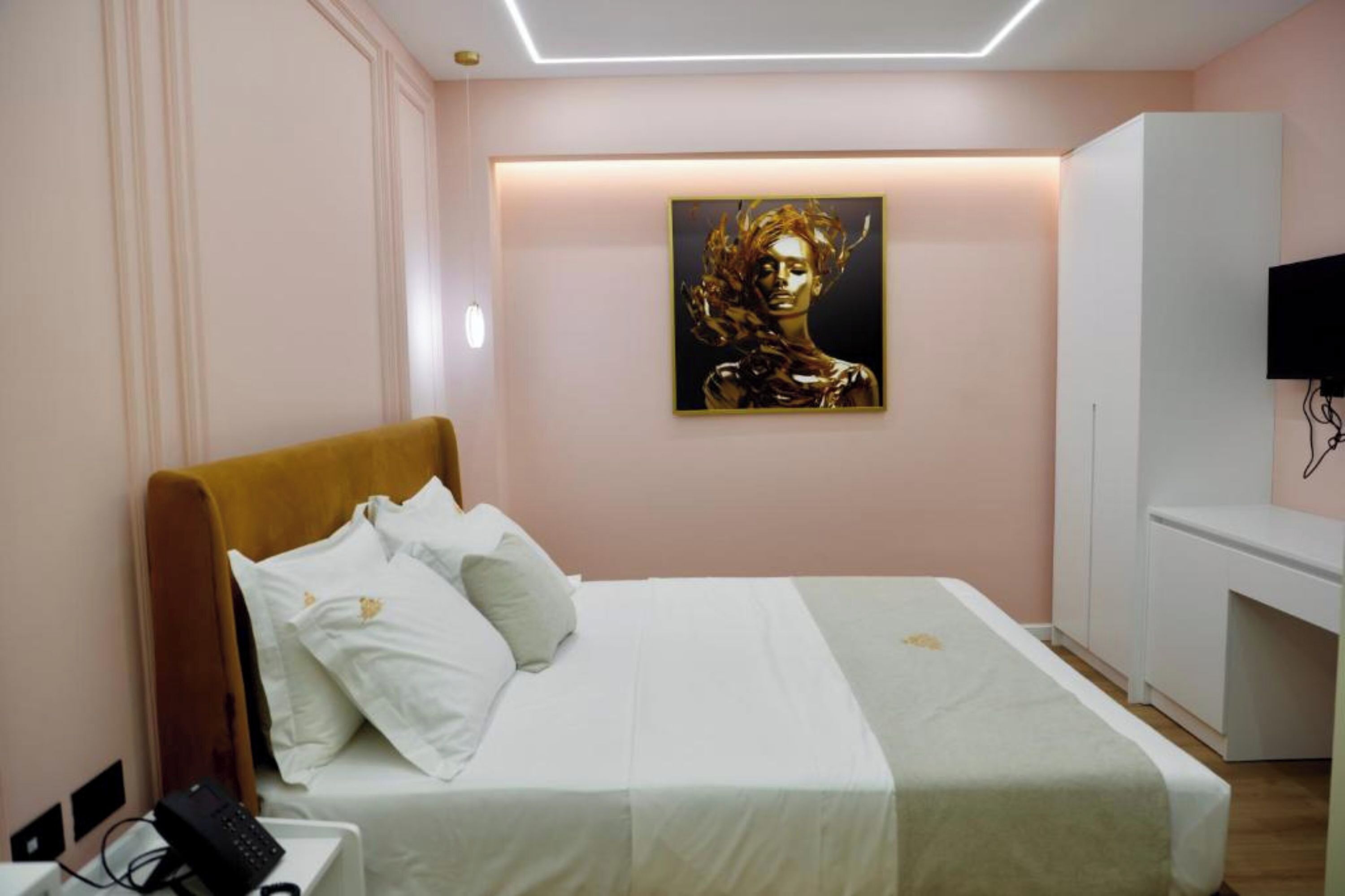 Una habitación de hotel con una cama, un teléfono en la mesita de noche, un cuadro en la pared y un televisor.