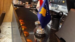 A bar area with a flag, shelves with bottles, and a counter.