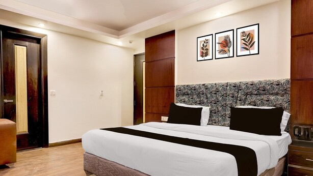 Un dormitorio con una cama grande, un armario de madera, un cabecero estampado y cuadros en la pared.
