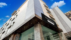 Un edificio moderno con un letrero llamativo que dice 'TOWHOUSE', ventanas grandes y una entrada en esquina.