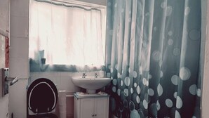 A bathroom with a toilet, sink, cabinet, and a window with curtains. - Room-cosy Private Room in Family Home ne (London)