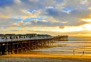 A pier extending into the ocean with buildings on one side and a sunset in the background. - Steps to Beach: Spa, BBQ, Bars & Dog Friendly (San Diego)