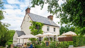 A traditional building with outdoor seating, a signboard, and greenery. - Canalside Hideaway in Berkhamsted - Pass the Keys (Berkhamsted)