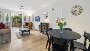 A modern living room with a dining area, a round table, and a clock on the wall. - Canalside Hideaway in Berkhamsted - Pass the Keys (Berkhamsted)