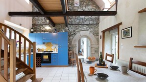 A kitchen with blue cabinets, a stone wall, and a dining area with a table set for two.