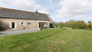 A stone building with a sloped roof, a gravel driveway, and a well-maintained lawn.