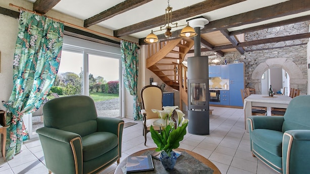 A living room with a fireplace, a dining area, and a staircase leading to an upper level.