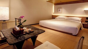 A hotel room with a bed, bedside table with a tray of tea, a potted orchid, and a wall-mounted TV. - Zhuhai Xumeishan Hotel  (Zhuhai)
