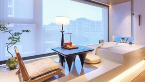 A modern bathroom with a large bathtub, a small table with a lamp, and a potted plant. - Zhuhai Xumeishan Hotel  (Zhuhai)