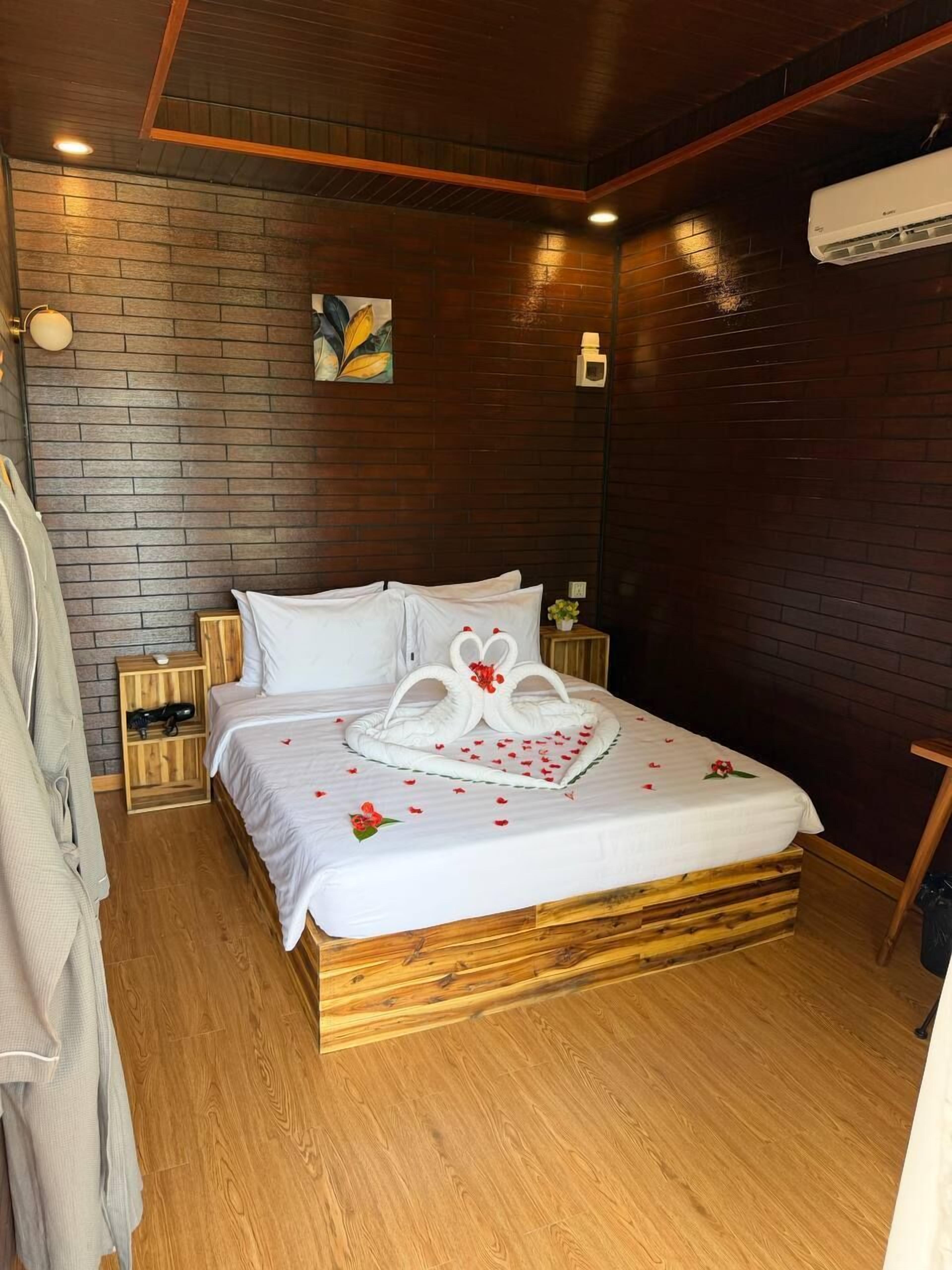 A neatly made bed with a heart-shaped decoration, wooden headboard, and a brick-patterned wall.