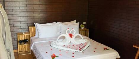Una cama bien hecha con una decoración en forma de corazón, cabecera de madera y pared con diseño de ladrillo.