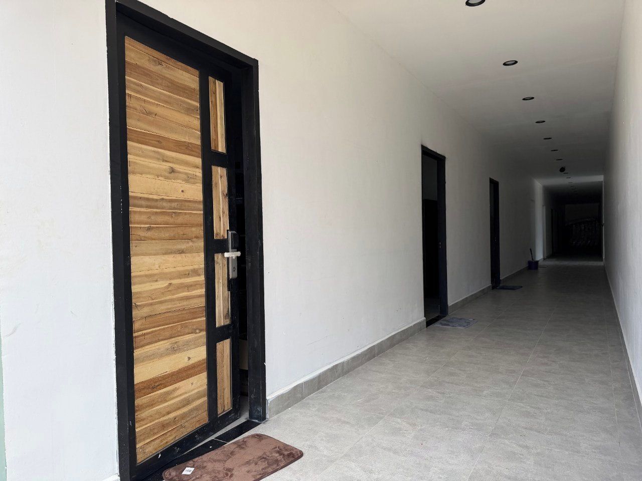 Un pasillo con una puerta de madera y un banco, que conduce a una habitación con suelo de baldosas.