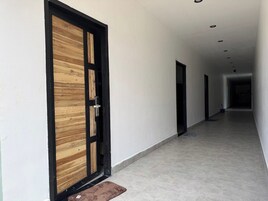 Un pasillo con una puerta de madera y un banco, que conduce a una habitación con suelo de baldosas.
