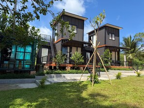 Una casa moderna a due piani con un balcone, una scalinata e un piccolo giardino.