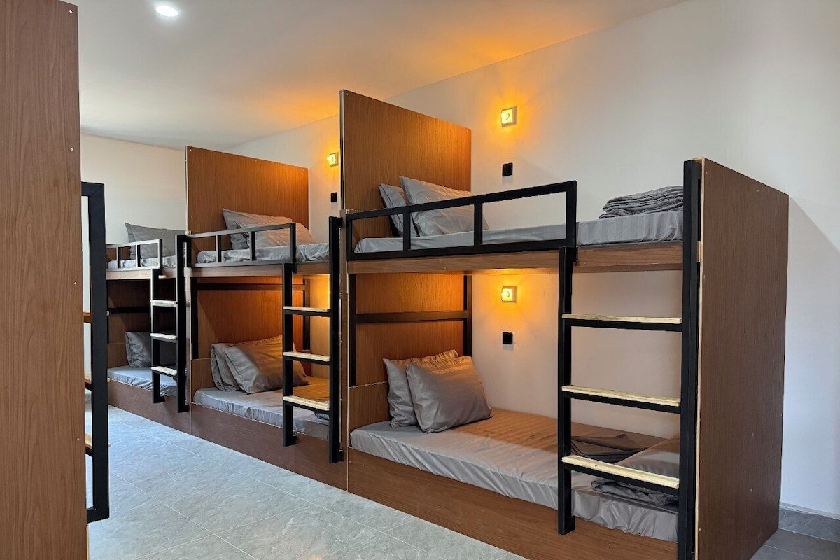 A room with bunk beds, wooden headboards, and wall-mounted lights.