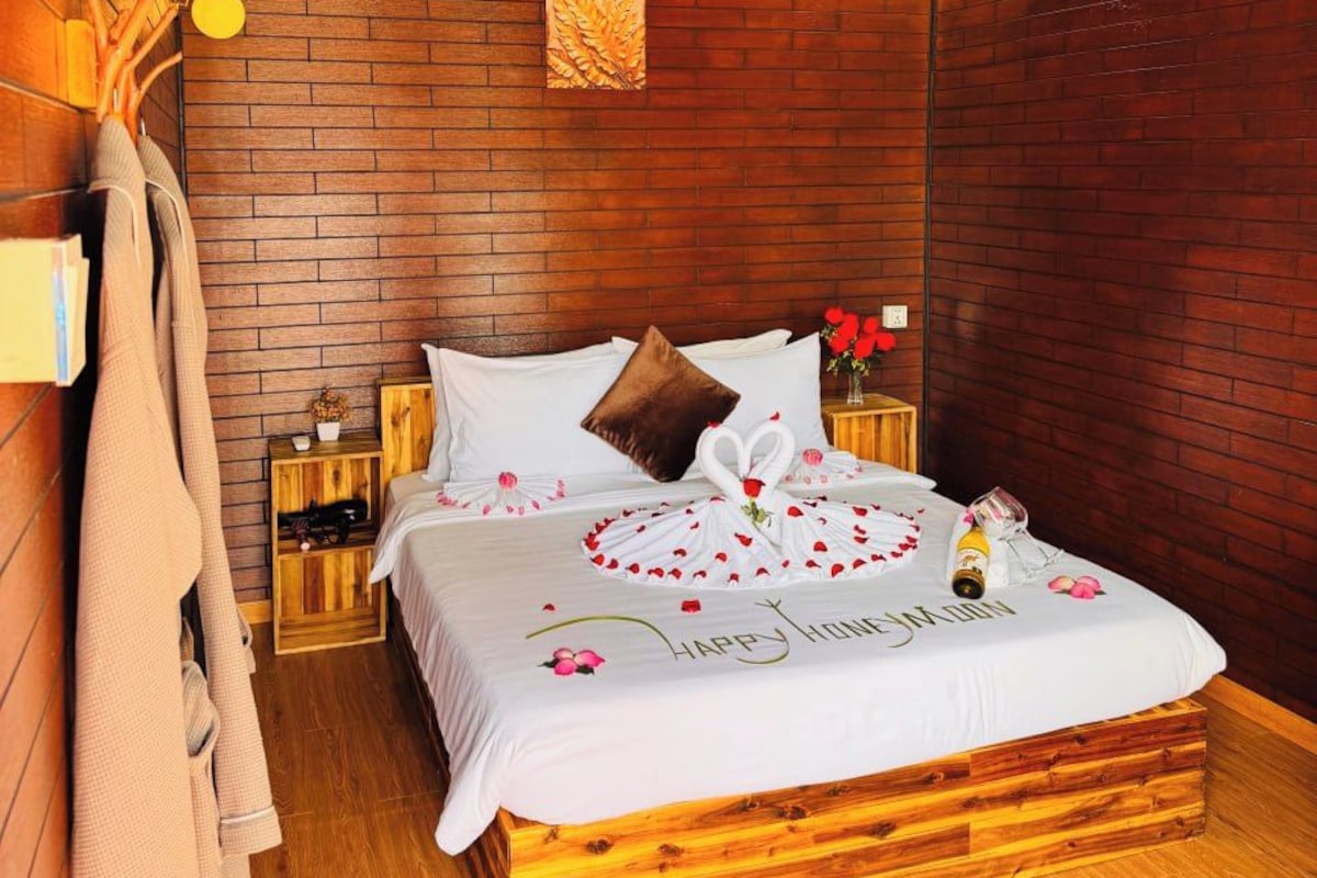 A cozy room with a wooden bed, a brick wall, and a wooden ceiling.