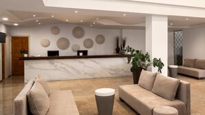 Una hall moderna con una reception in marmo, divani e una pianta in vaso.