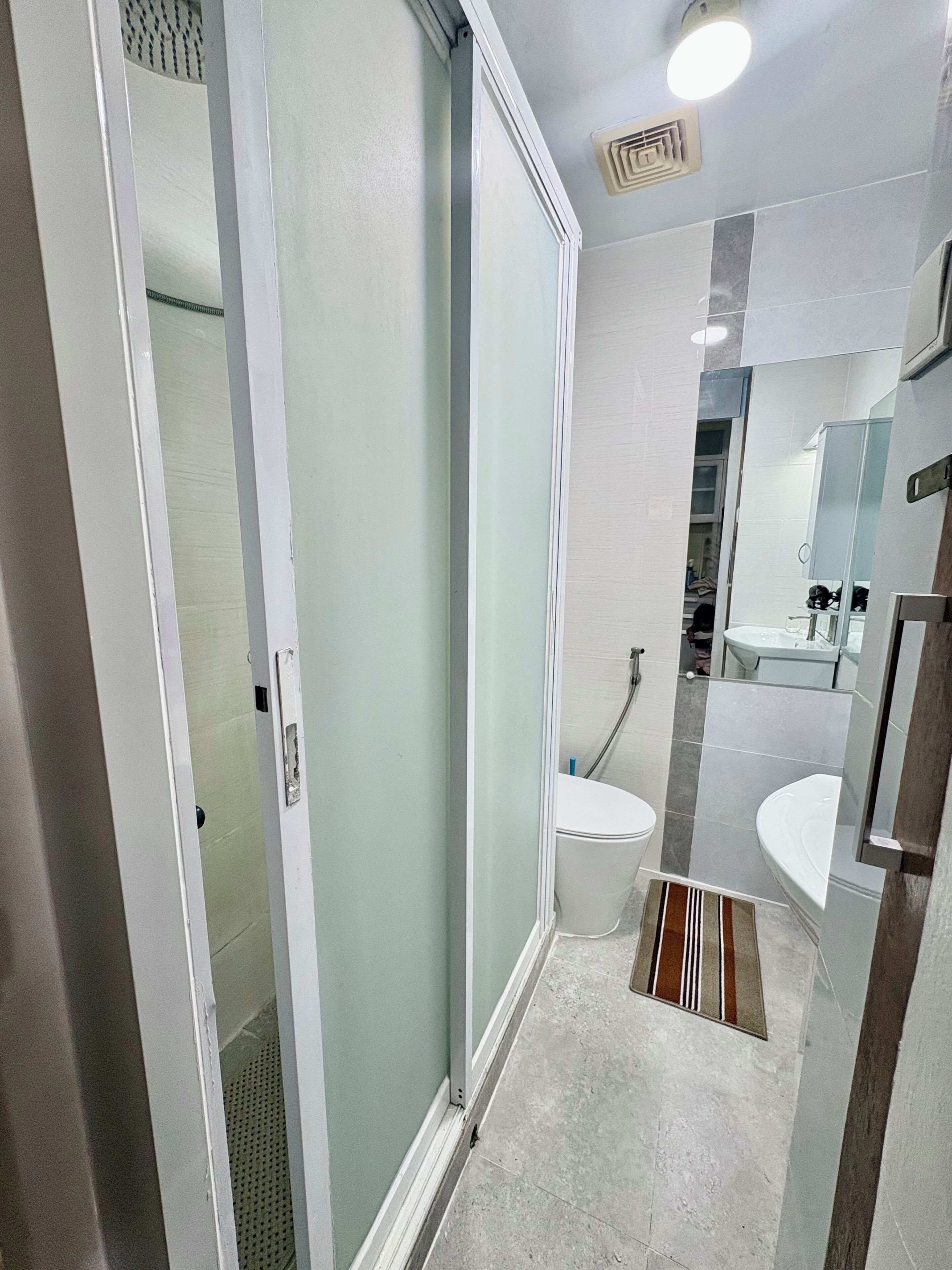Une salle de bain moderne avec une douche à parois de verre, des toilettes blanches, un lavabo et un miroir.