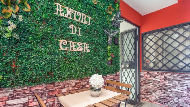 A wall with greenery and a bench with a vase.