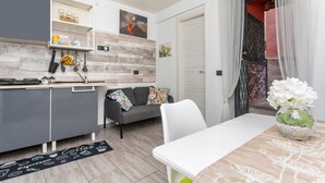 A modern kitchen with grey cabinets, a white countertop, and a black coffee-themed rug.