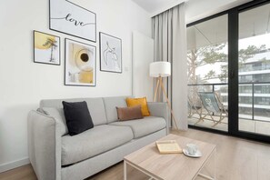 Ein modernes Wohnzimmer mit einem grauen Sofa, einem Couchtisch und gerahmten Kunstwerken an der Wand.