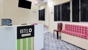 A hotel reception area with a reception desk, a clock, a television, and a sofa. - Deluxenimalan Residency (Chennai)