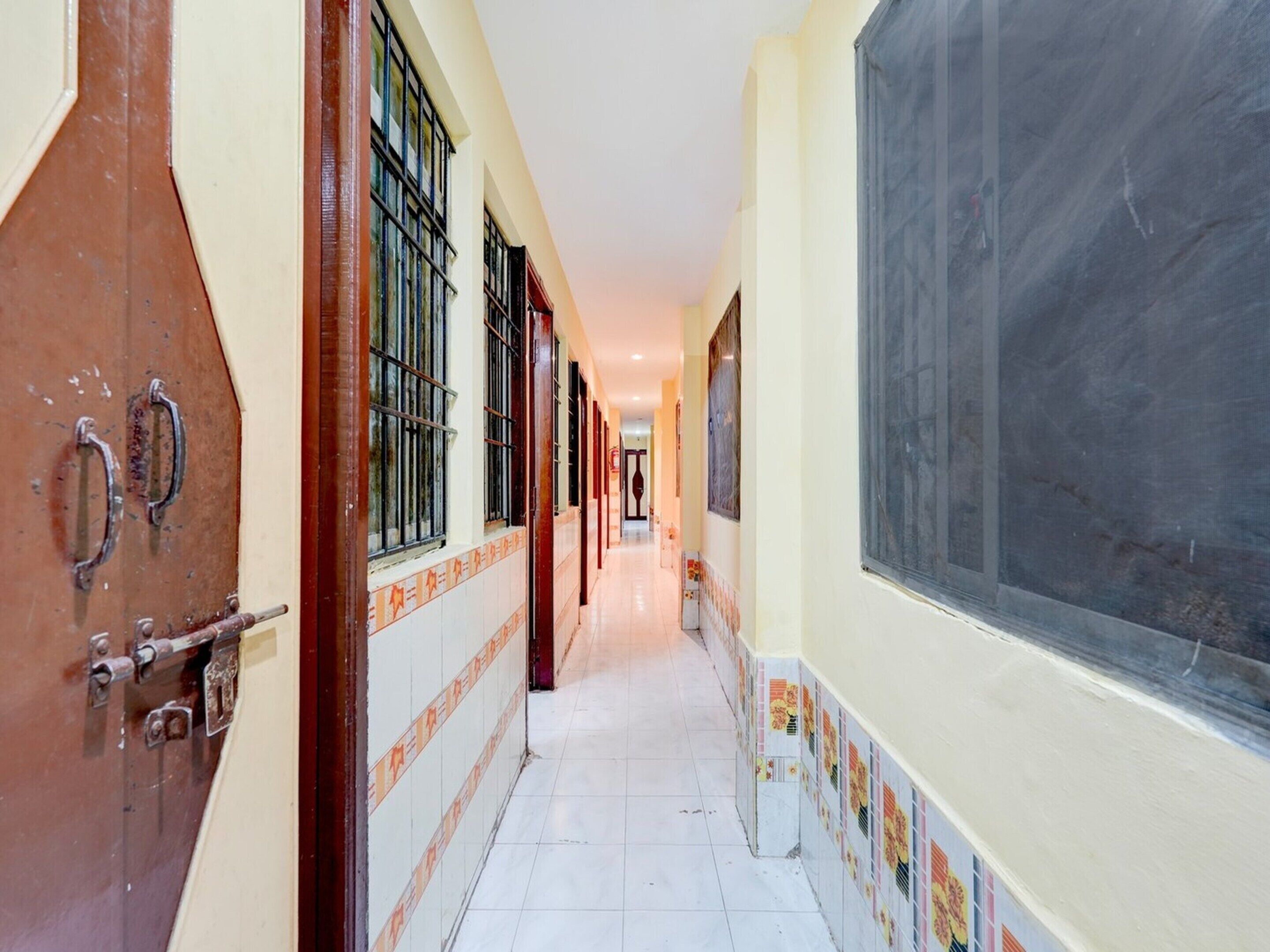 A corridor with tiled walls, a large window, and a door with a metal handle.