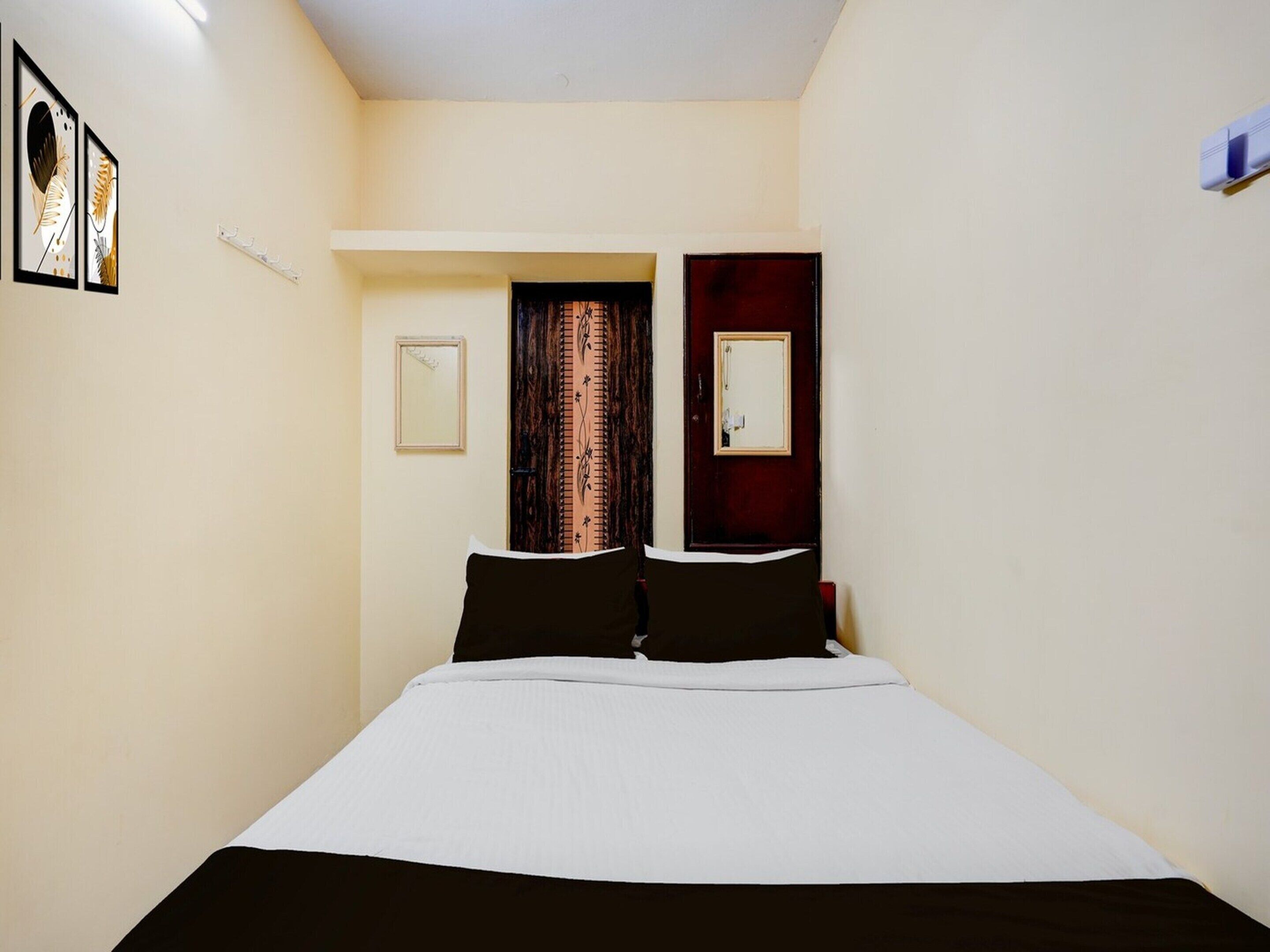 Un dormitorio con una cama, dos puertas, un espejo y un cuadro enmarcado en la pared.