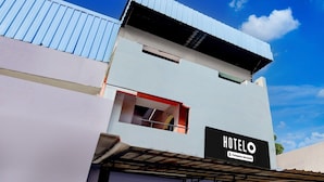 A modern hotel building with a prominent 'HOTEL' sign, a visible window, and a metal roof. - Deluxenimalan Residency (Chennai)