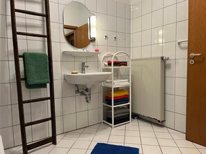 Une salle de bain avec un lavabo blanc, un miroir, un porte-serviettes et un radiateur.