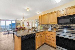 A kitchen with wooden cabinets, a microwave, an oven, and a dishwasher. - 🌊Buena Vista 203 | Balcony w/Gulf Views + Community Pool | Beachfront Complex (Gulf Shores)