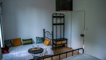 Une pièce comprenant un lit, une petite table, un luminaire suspendu, une chaise et une porte.