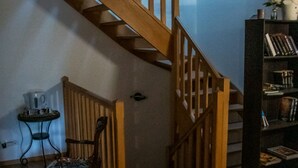 A wooden staircase in a room with a chair and a small table. - maison d'hôtes Lacour (Augignac)