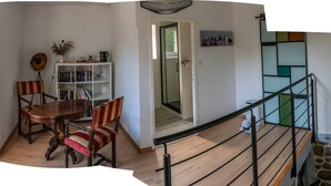 A dining area with a wooden table and chairs, a bookshelf, and a staircase with a railing. - maison d'hôtes Lacour (Augignac)