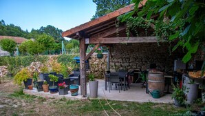 A stone patio with outdoor furniture, potted plants, and a wooden pergola. - maison d'hôtes Lacour (Augignac)