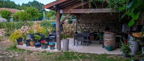 A stone patio with outdoor furniture, potted plants, and a wooden pergola.