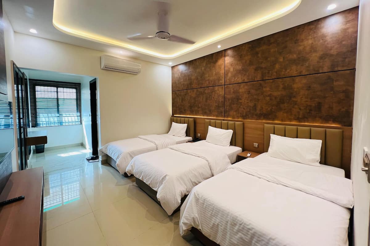 Habitación de hotel con dos camas, ventilador de techo, iluminación empotrada y una pared decorativa de madera.