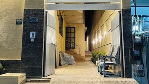 A hotel entrance with a covered staircase, a reception desk, and a seating area with chairs. - Heritage Heaven (Karachi)