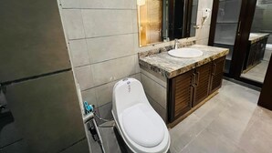 A modern bathroom with a toilet, sink, and mirror. - Heritage Heaven (Karachi)