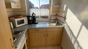 Une cuisine compacte équipée d’un four à micro-ondes, d’une machine à café et d’un évier.
