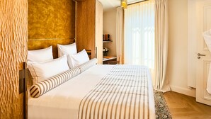 A hotel room with a large bed, a wooden headboard, a desk with a chair, and a window with curtains. - Étoile Park Hôtel (Paris)