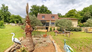Ein Haus mit Garten, einer Vogel-Skulptur und einem Baum.