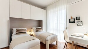 A modern hotel room with two beds, a desk, and a chair. - Ruan Downtown (Como)