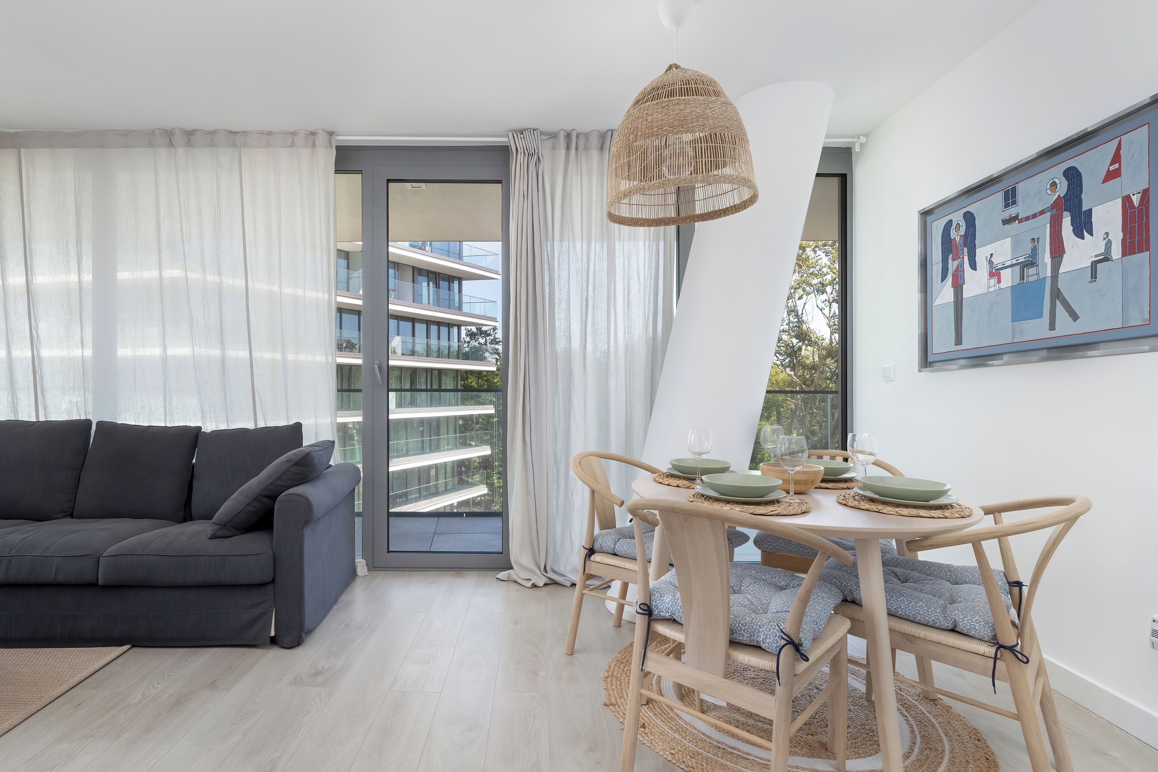 Una sala de estar moderna con sofá, mesa de comedor, sillas y un ventanal grande.