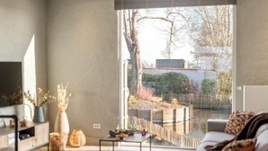 Un salon moderne avec une grande fenêtre, un canapé, une table basse et des objets de décoration.