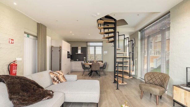 Un salon moderne comprenant un canapé, un coin repas, une cuisine et un escalier en colimaçon.