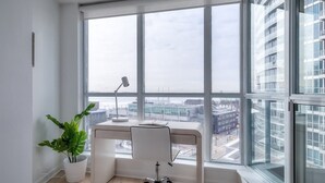Un espacio de oficina moderno con un amplio ventanal, un escritorio, una silla y una planta en maceta.