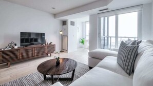 Una sala de estar moderna con un sofá, una mesa de centro, un televisor y un mueble bajo de madera.