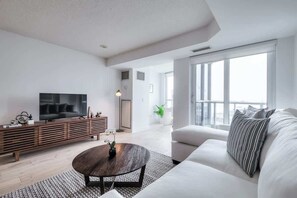 Ein modernes Wohnzimmer mit einer Couch, einem Couchtisch, einem Fernseher und einer Holzunterhaltungseinheit.