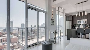 A modern apartment with large windows, a kitchen, and a seating area with a view of the city.